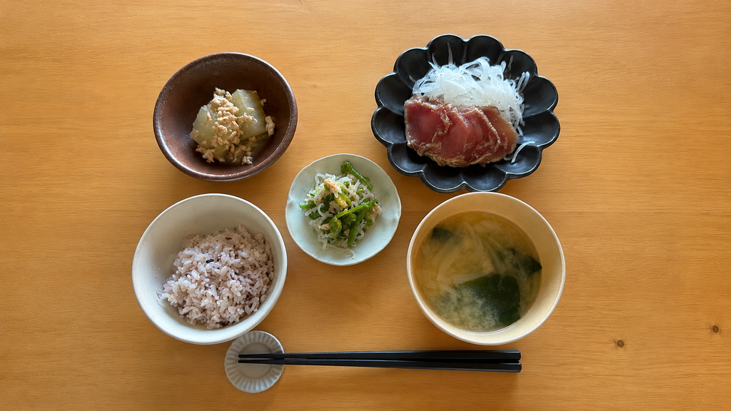 家庭料理の夕食。ご飯、味噌汁、刺身、小鉢のおかずなどが並んでいる